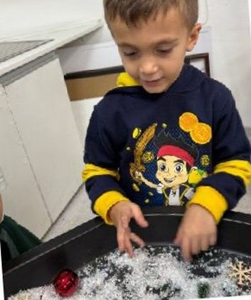 A child exploring a sensory tray of fake snow