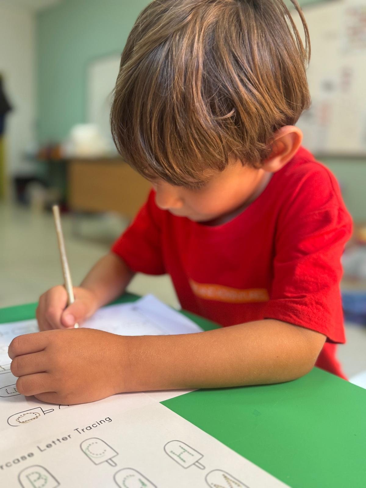 A child concentrating on a drawing at the craft table