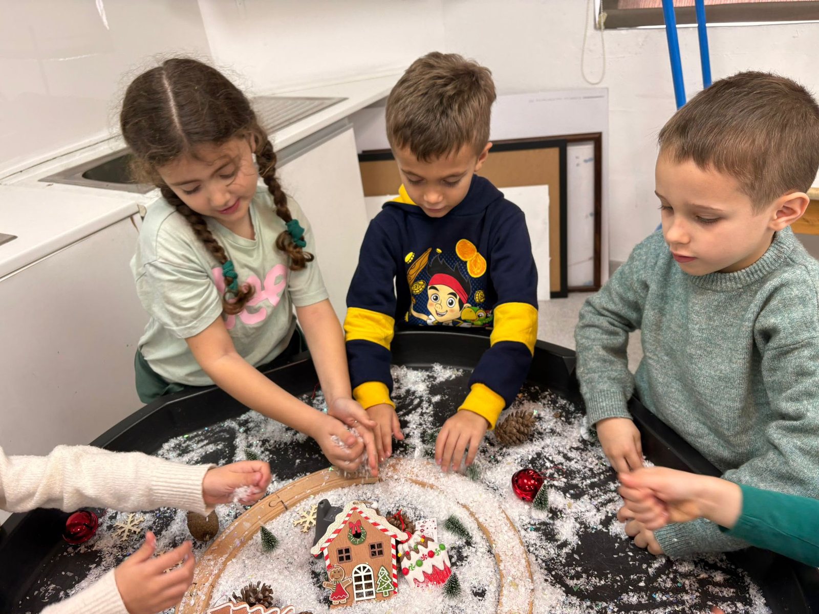 Two children decorating a gingerbread house together