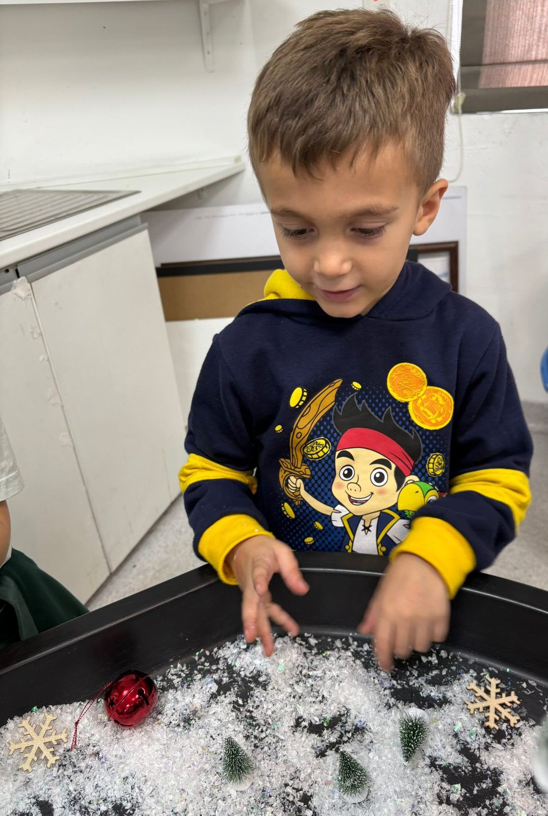 A child exploring a sensory tray of fake snow
