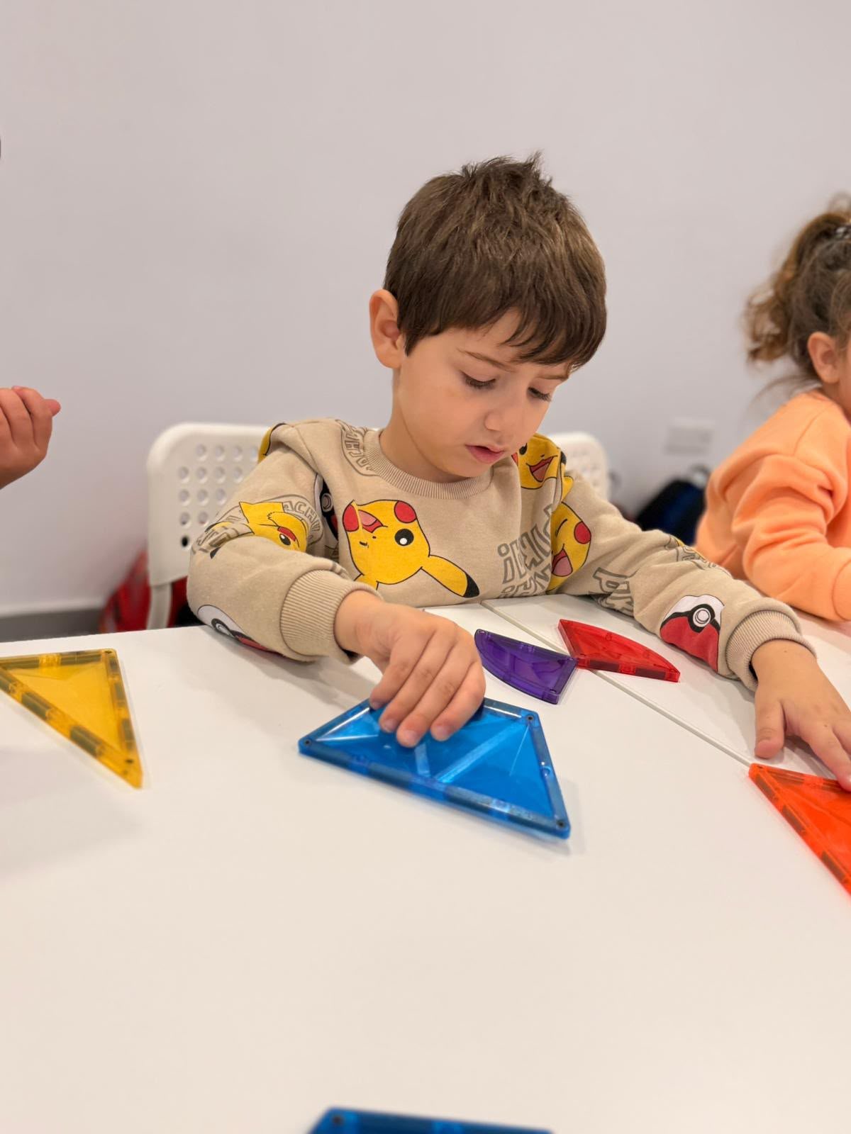 A child sorting bright shapes with a friend nearby