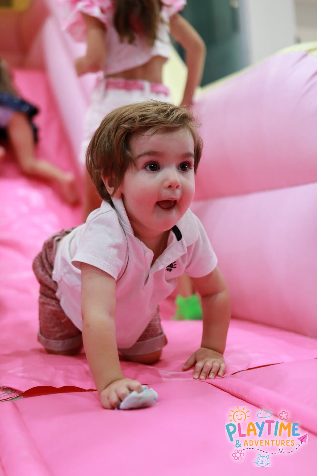 A toddler crawling happily on the pink bouncy castle