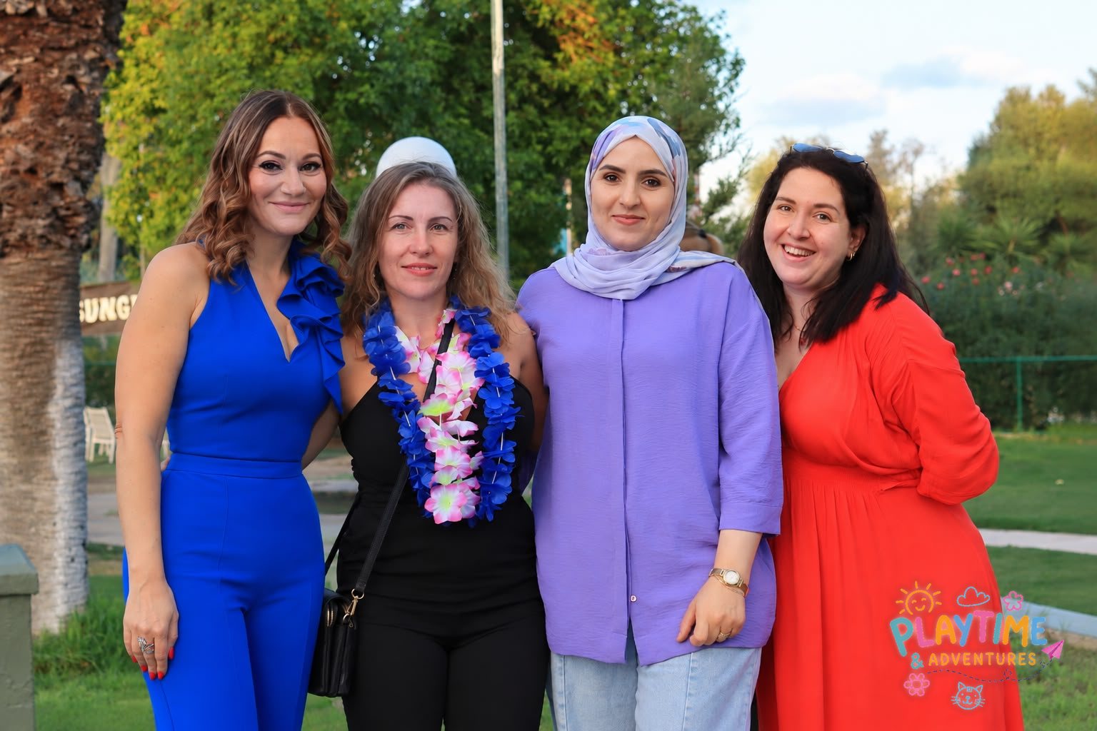 Four friends posing together in the sunshine at the Summer Party